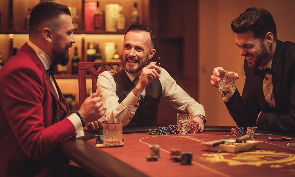 a trio of men laughing while drinking and gambling